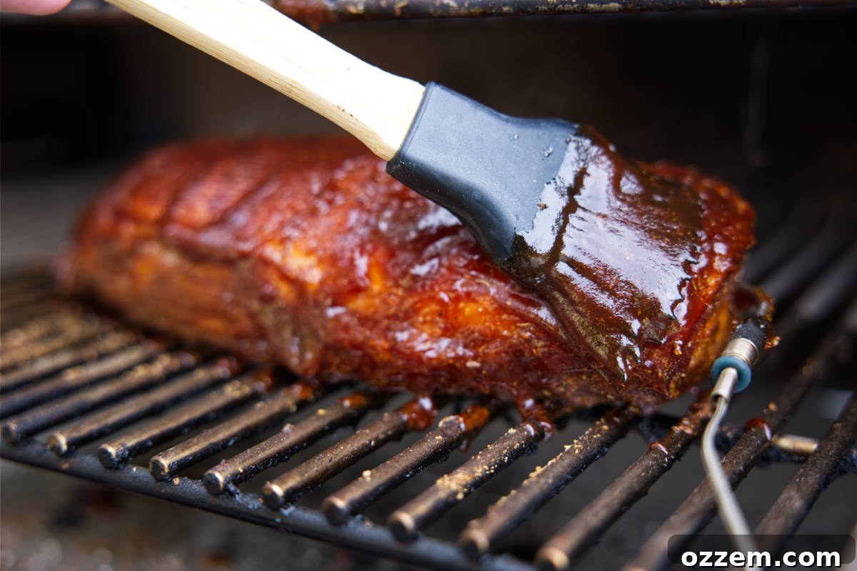 Brushing BBQ sauce on smoked pork loin.