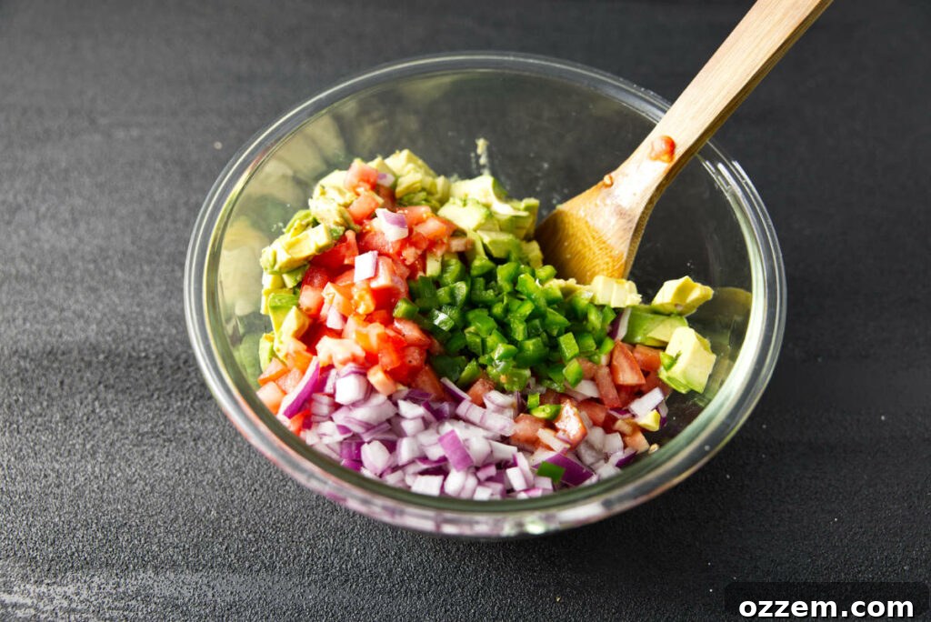 Pork Loin Taco Remix 5 Finely diced red onion, ripe Roma tomatoes, creamy Hass avocado, and spicy jalapeño peppers being gently combined in a large glass bowl to form the vibrant avocado salsa.