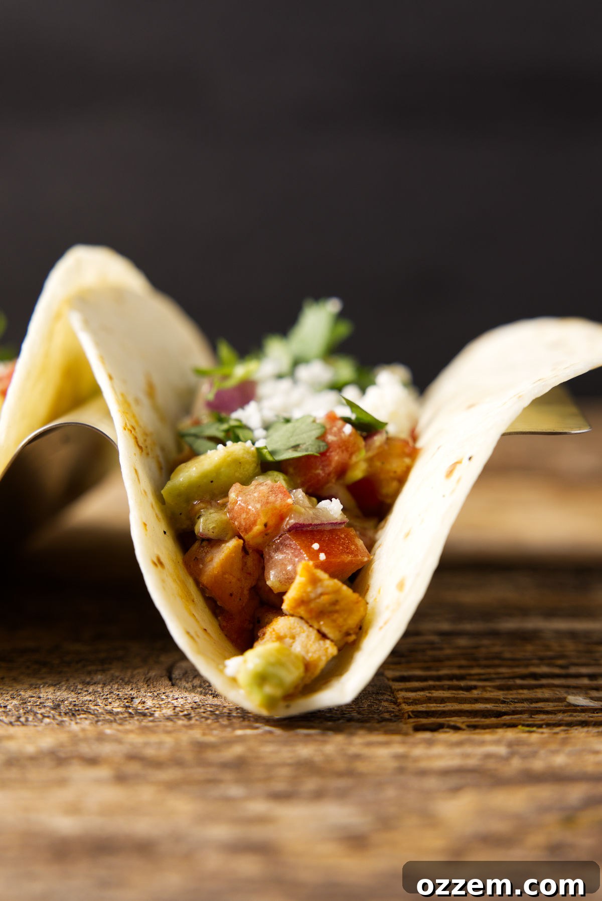 Pork Loin Taco Remix 7 Close-up front view of two perfectly assembled leftover pork loin tacos, loaded with tender pork, fresh avocado salsa, and generously topped with crumbled queso fresco, ready to be enjoyed.