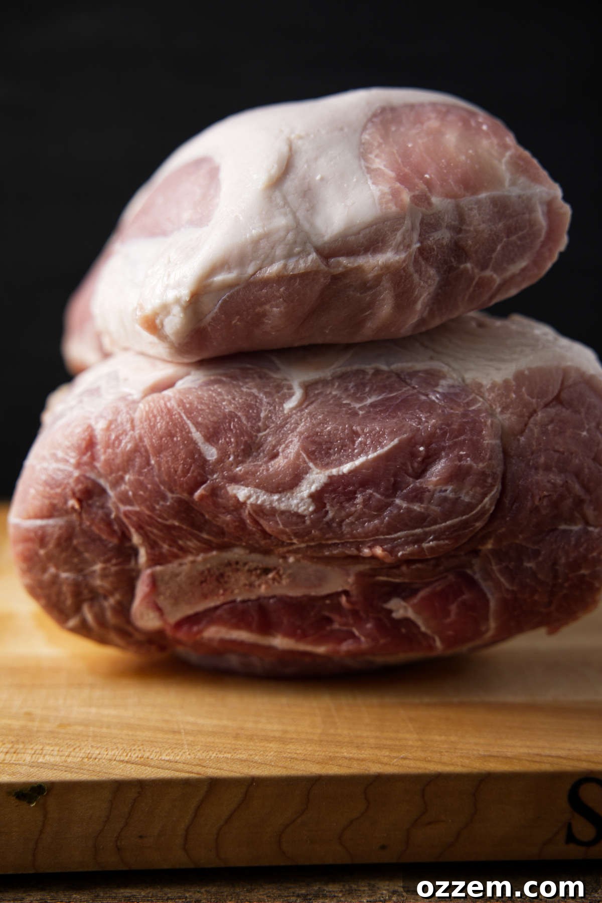 The Pork Loin Shoulder Showdown 2 Pork loin on top of a pork shoulder sitting on a butcher block.