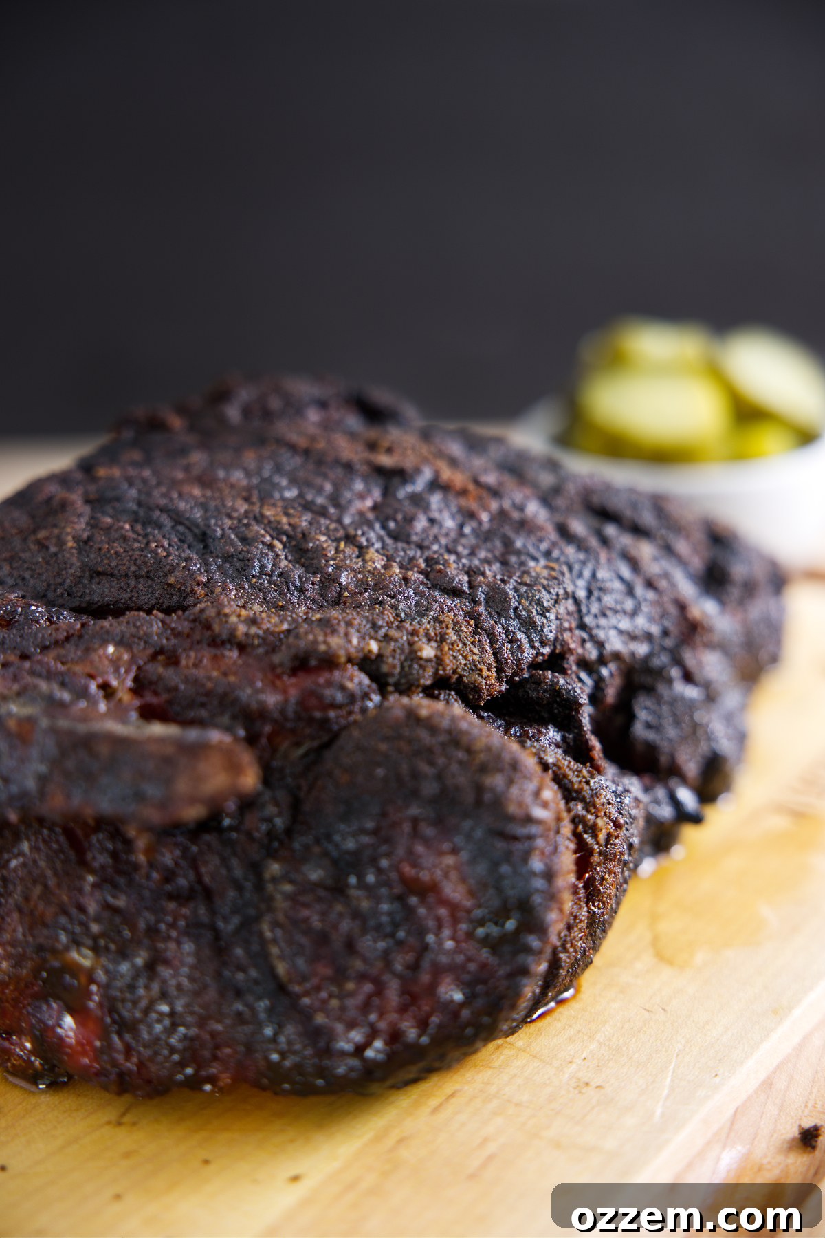 The Pork Loin Shoulder Showdown 6 Pork butt resting on cutting board with some pickles in the background.