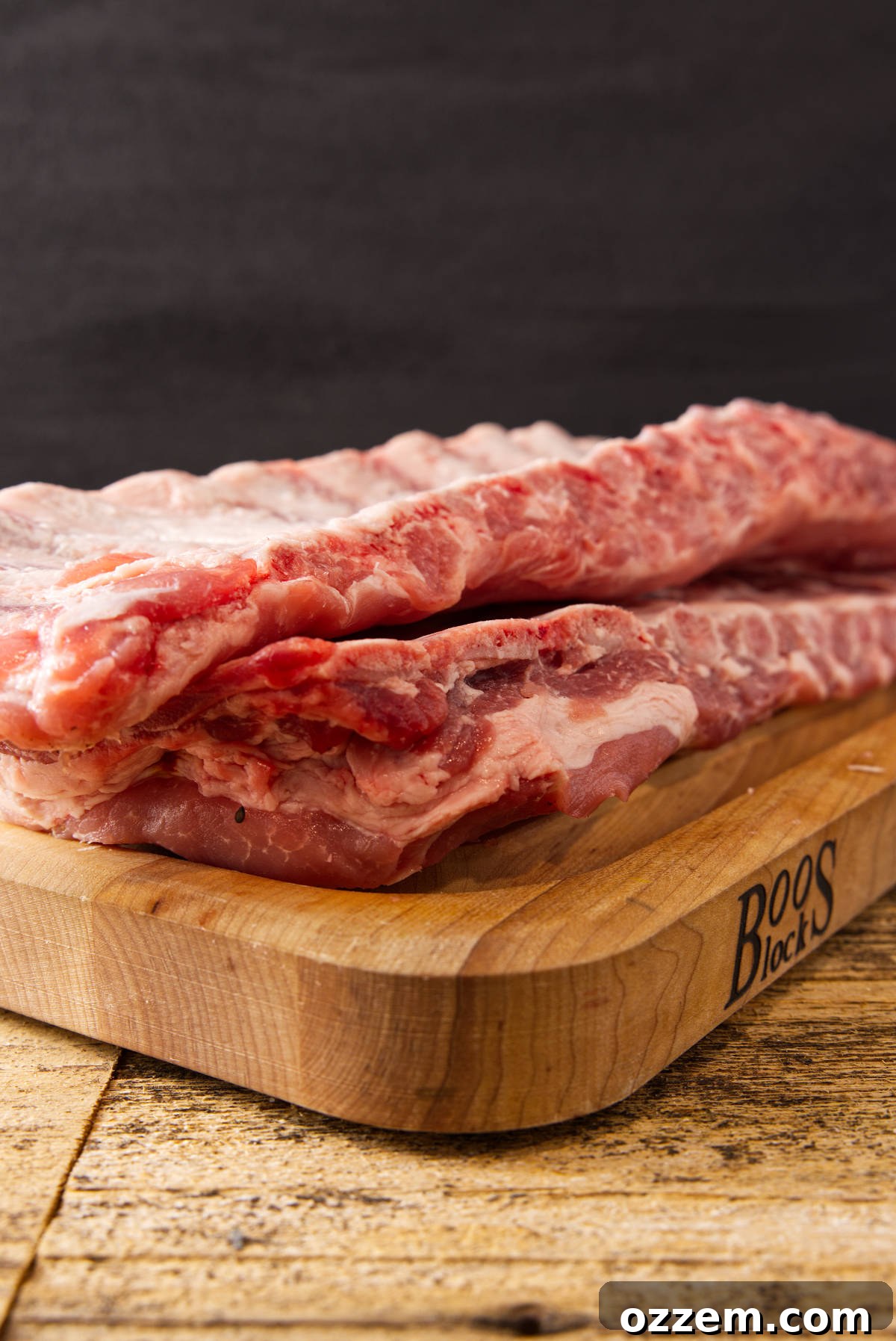 Pork loin back ribs vs spare ribs stacked on top of eachother on butcher block.