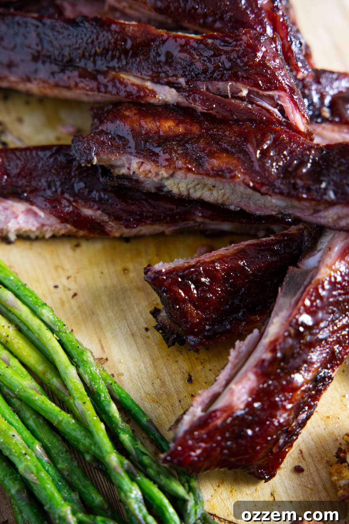 sliced traeger 3-2-1 ribs on cutting board with asparagus