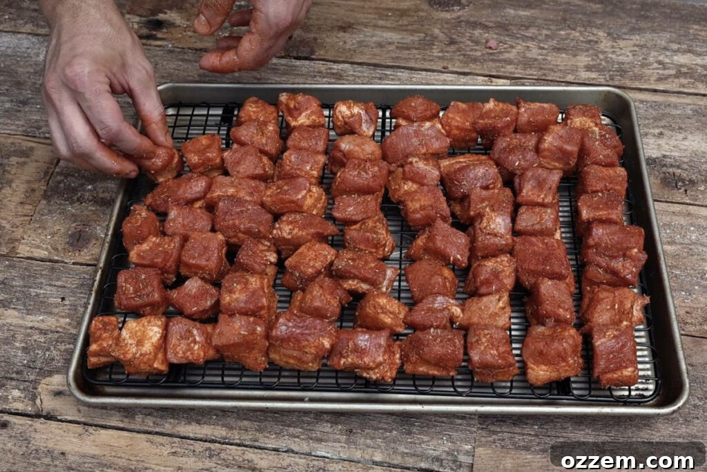 Cubed pork belly spread out on a wire rack, ready to be placed on the smoker for even cooking and smoke penetration.