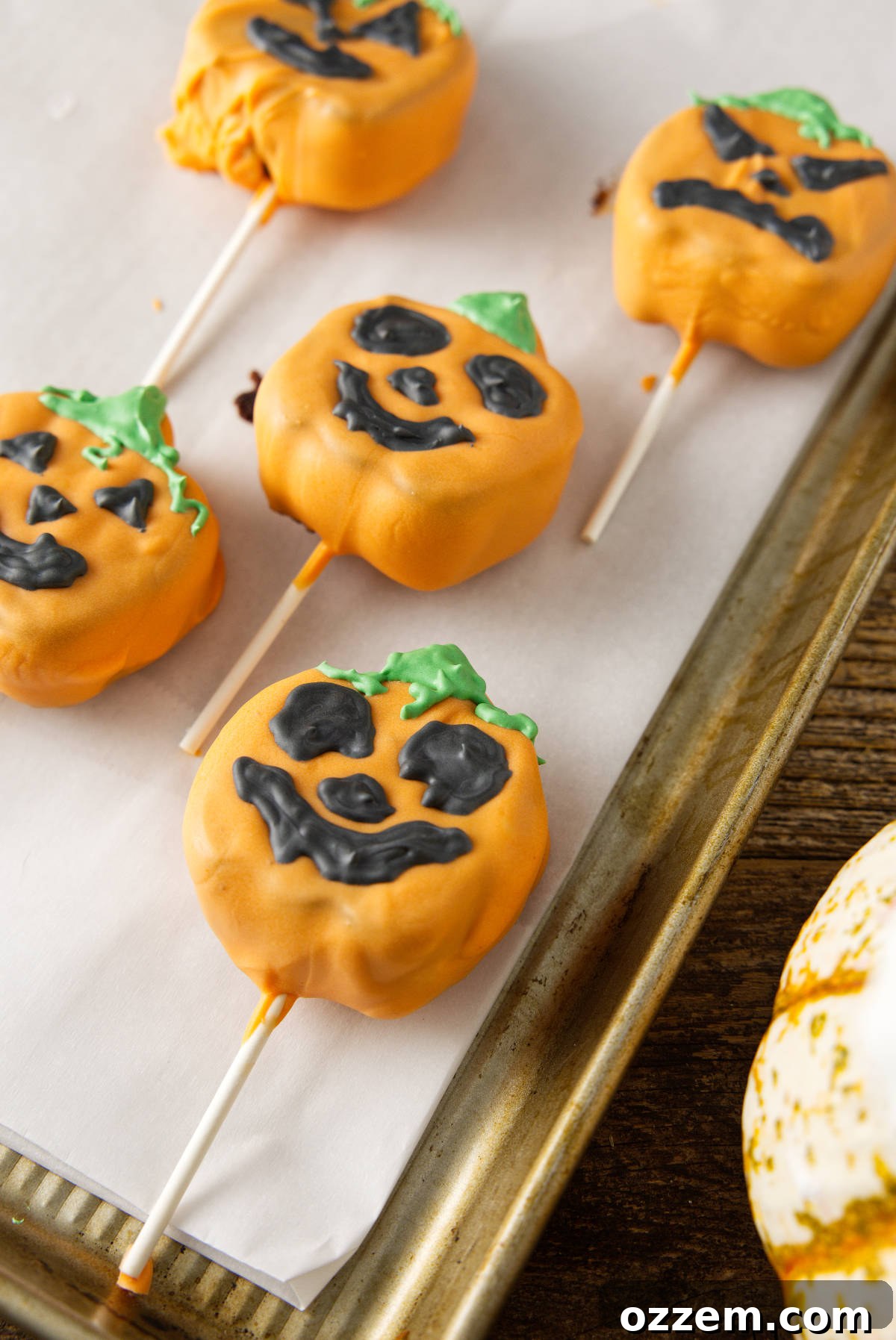 Jack-o'-lantern cake pops on cookie sheet.