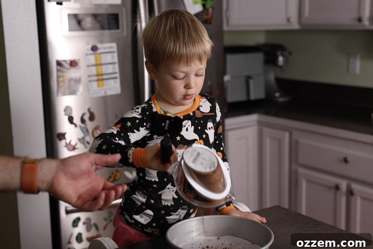 Preparing cake pan with grease, parchment paper, and cocoa powder.
