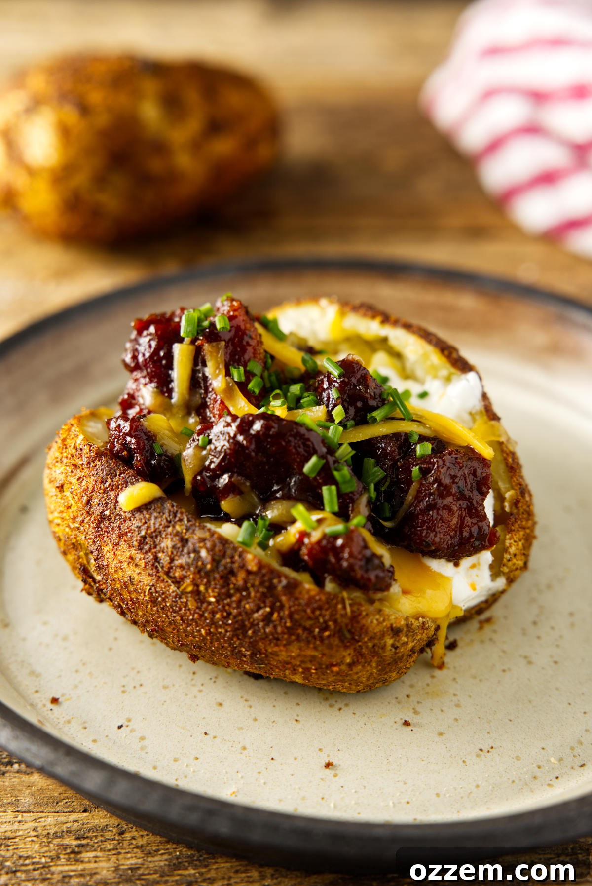 Plated fully loaded baked potato mounded with brisket and melted cheese.