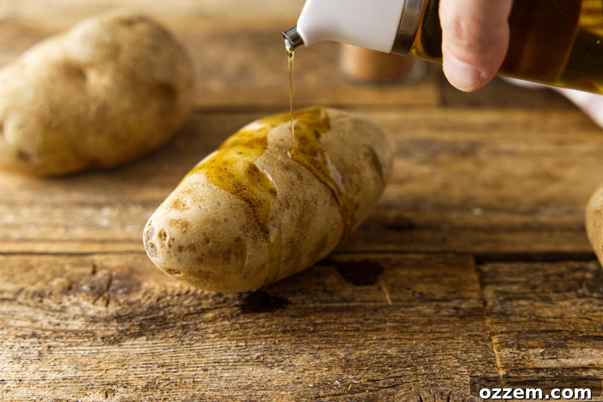 Drizzling olive oil on russet potatoes.