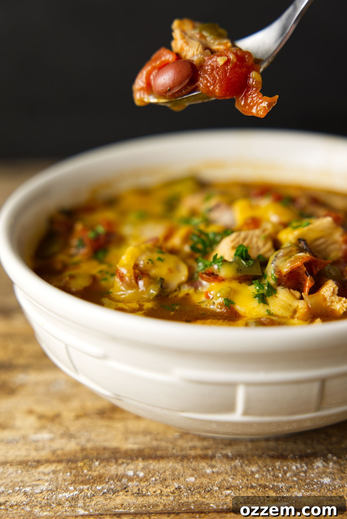 Smoky Leftover Turkey Chili 2 A spoonful of turkey chili, loaded with chunks of leftover turkey, tomatoes, beans, cheese and parsley.