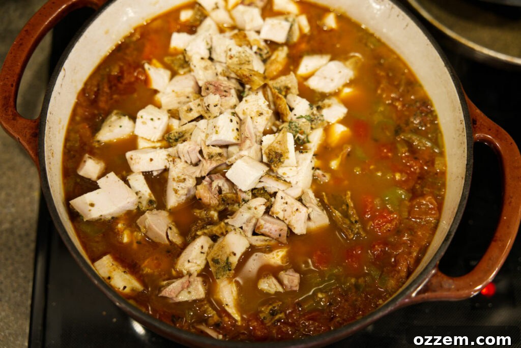 Smoky Leftover Turkey Chili 6 Adding leftover turkey to the chili in a Dutch oven.