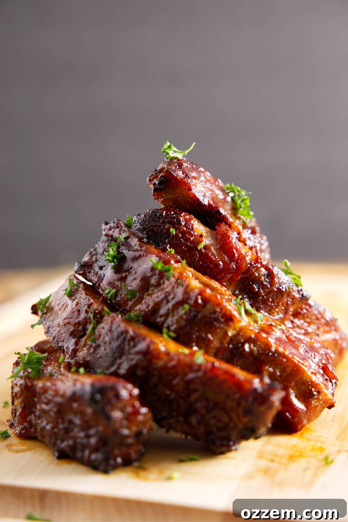 Stack of saucy BBQ pork ribs, glistening with sauce and ready to be enjoyed.