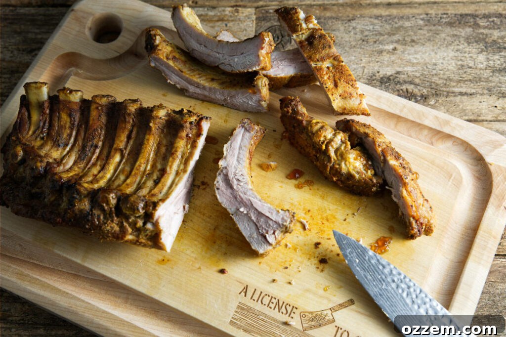 Cutting up a large slab of pork ribs on a wooden cutting board into individual portions.