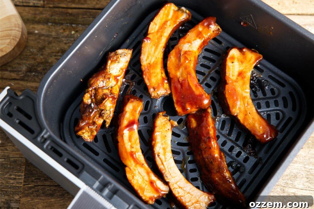 Individual sauced pork ribs neatly placed in an air fryer basket, ready for cooking.