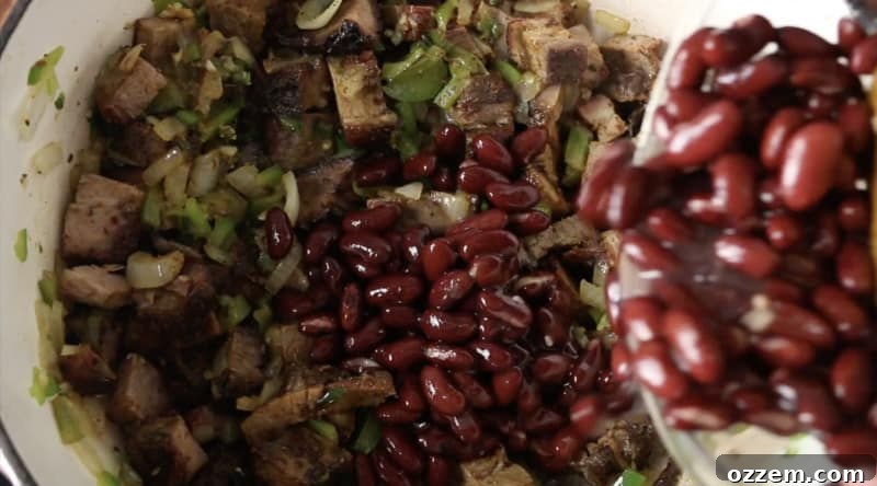 red kidney beans being poured into base of smoked brisket chili