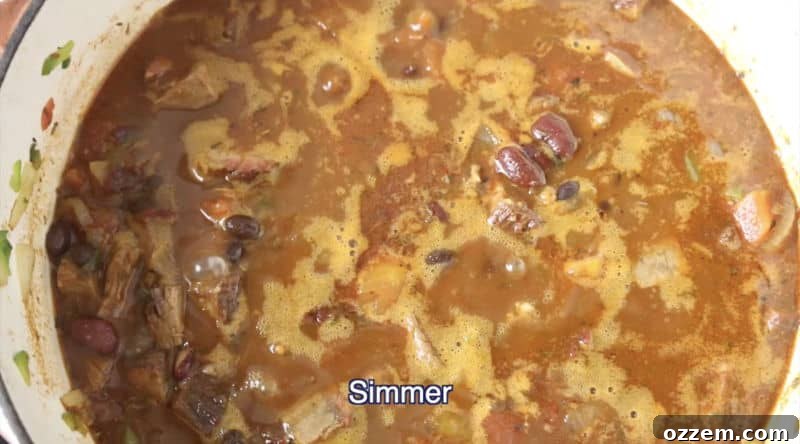 dutch oven filled with smoked brisket chili being simmered on low-medium heat burner