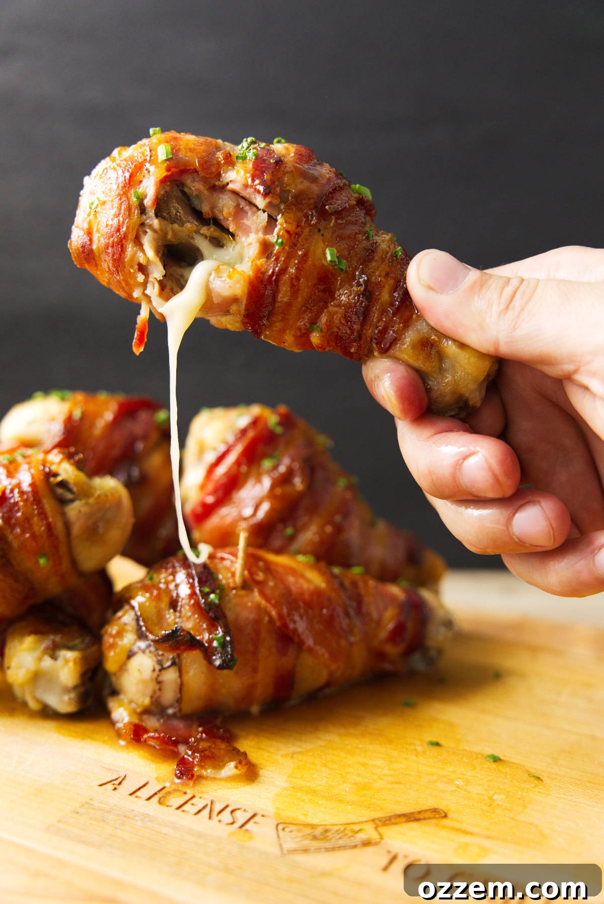 Smoky Traeger Stuffed Chicken Legs 2 Holding a stuffed chicken leg with a bite taken out of it and melty cheese oozing out.