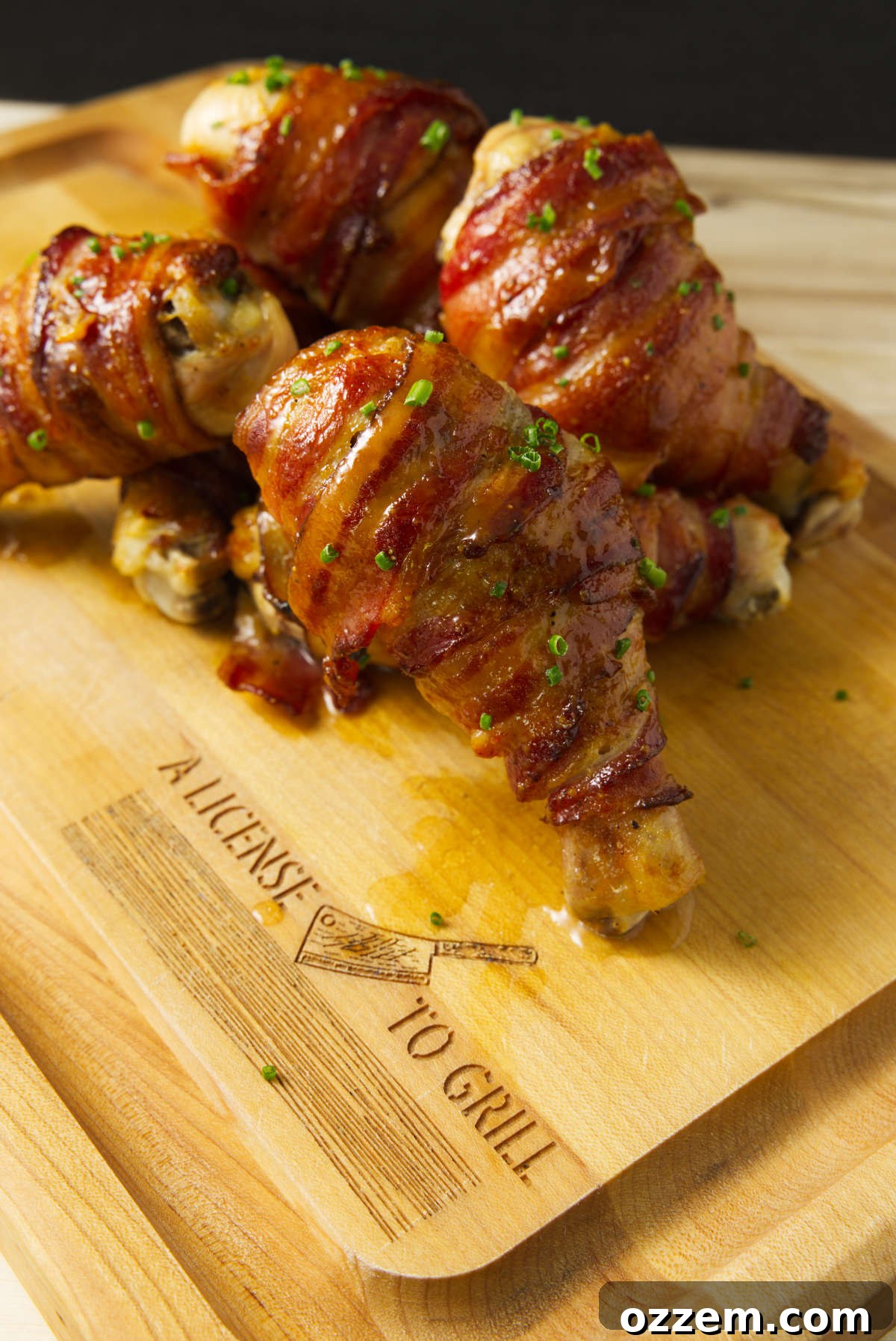 Smoky Traeger Stuffed Chicken Legs 5 Bacon wrapped smoked stuffed chicken legs stacked on a cutting board.