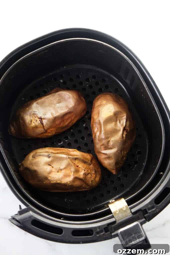 Air Fryer Sweet Potato Perfection 3 Three perfectly scrubbed sweet potatoes placed neatly inside an air fryer basket, ready for baking.