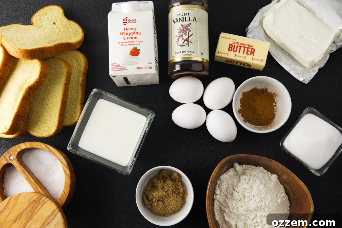 Various ingredients for an overnight French toast casserole laid out on a kitchen counter, including brioche bread, eggs, milk, cream cheese, sugars, and spices.