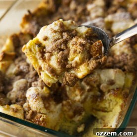 A close-up image of a generous scoop of Overnight French Toast Casserole, showcasing its golden crust and soft, creamy interior.