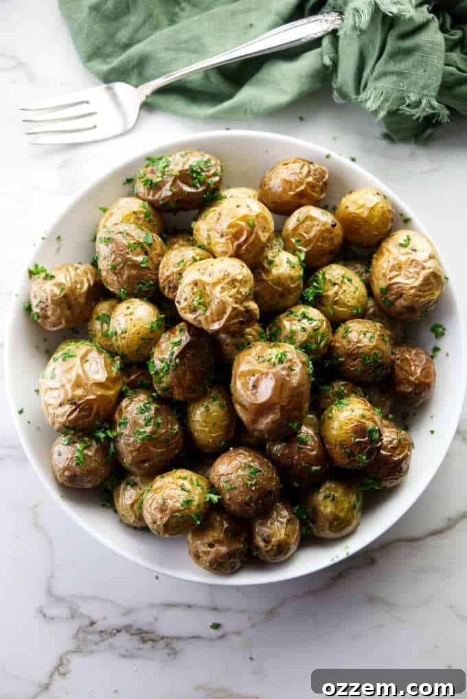 A serving dish of baby parsley potatoes, garnished with fresh herbs.