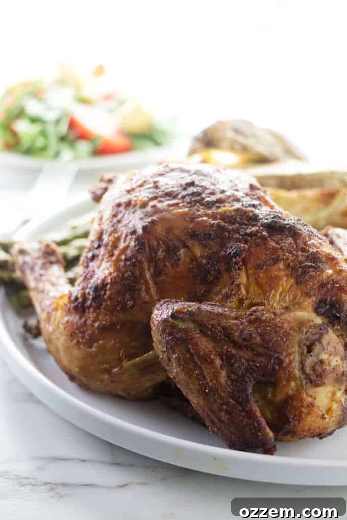 Perfectly roasted Air Fryer Cornish game hen served with a fresh green salad in the background, highlighting its golden-brown, crispy skin and appealing presentation.