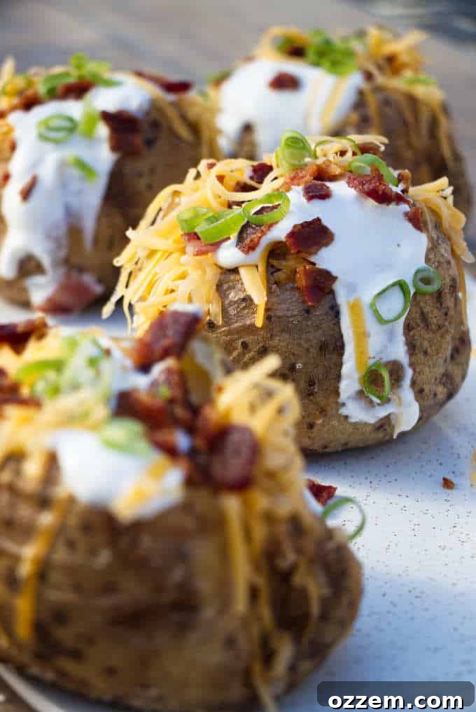 The Ultimate Air Fryer Baked Potato 4 Air fryer baked potatoes on a serving platter with various toppings in bowls around them