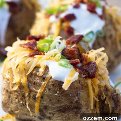 4 air fryer baked potatoes topped with sour cream, cheese, bacon and onions