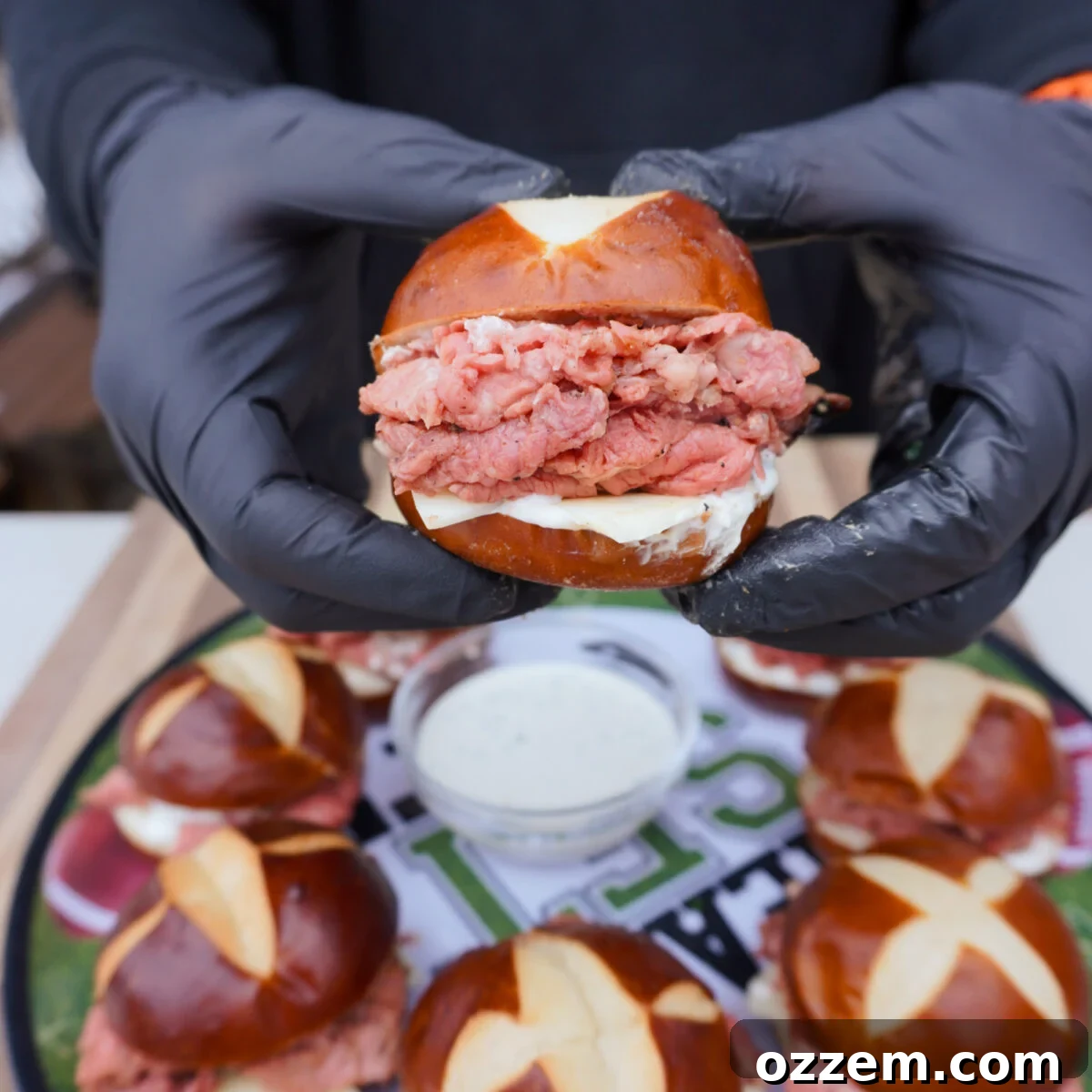 Gourmet Prime Rib Sliders 11 A close-up shot of a hand holding a perfectly assembled Grilled Prime Rib Slider, showcasing the layers of meat, cheese, and sauce.
