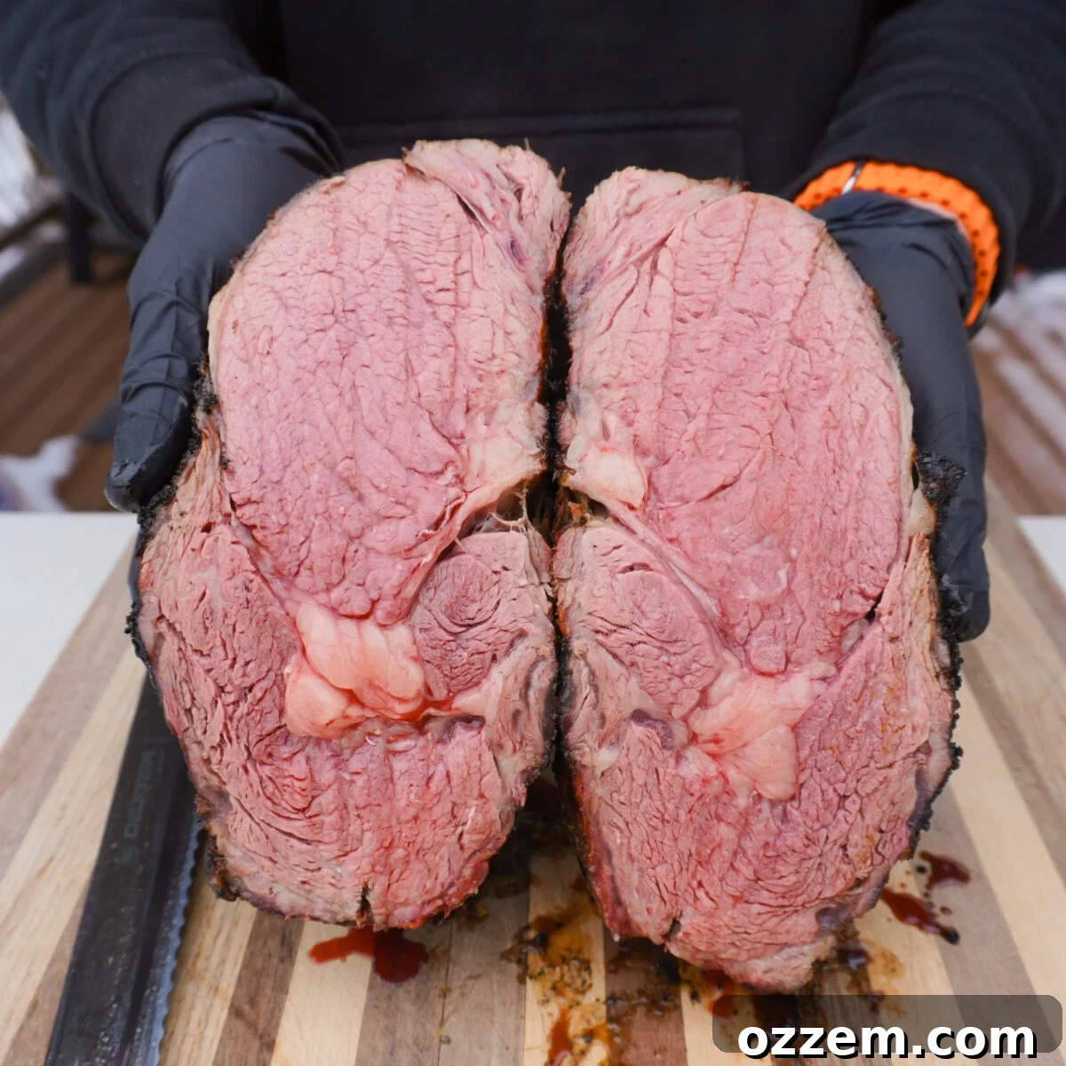 Gourmet Prime Rib Sliders 9 A perfectly grilled and seared prime rib, sliced in half to reveal a flawless medium-rare interior, resting on a cutting board.