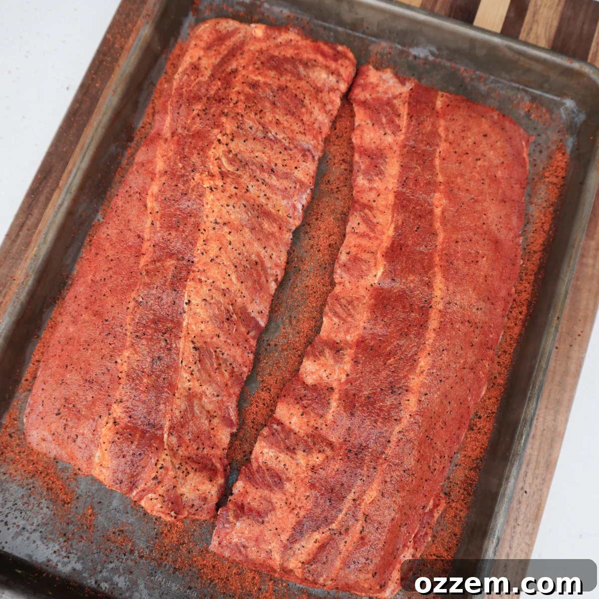 Close-up of baby back ribs generously seasoned, ready for smoking.