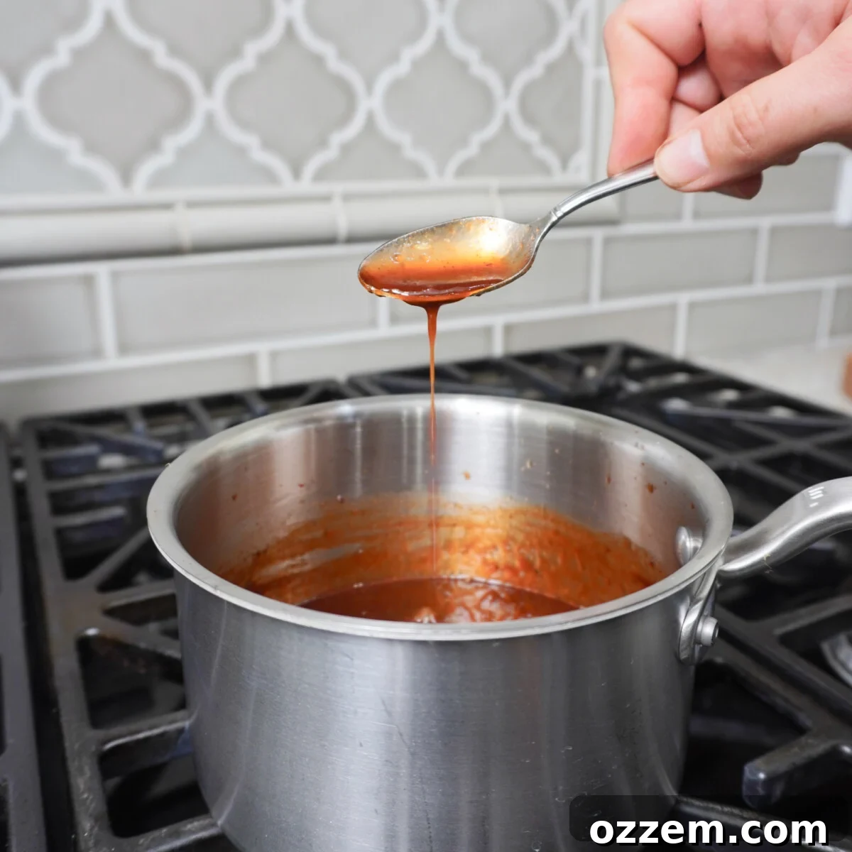 Homemade BBQ sauce simmering in a saucepan over the stove.