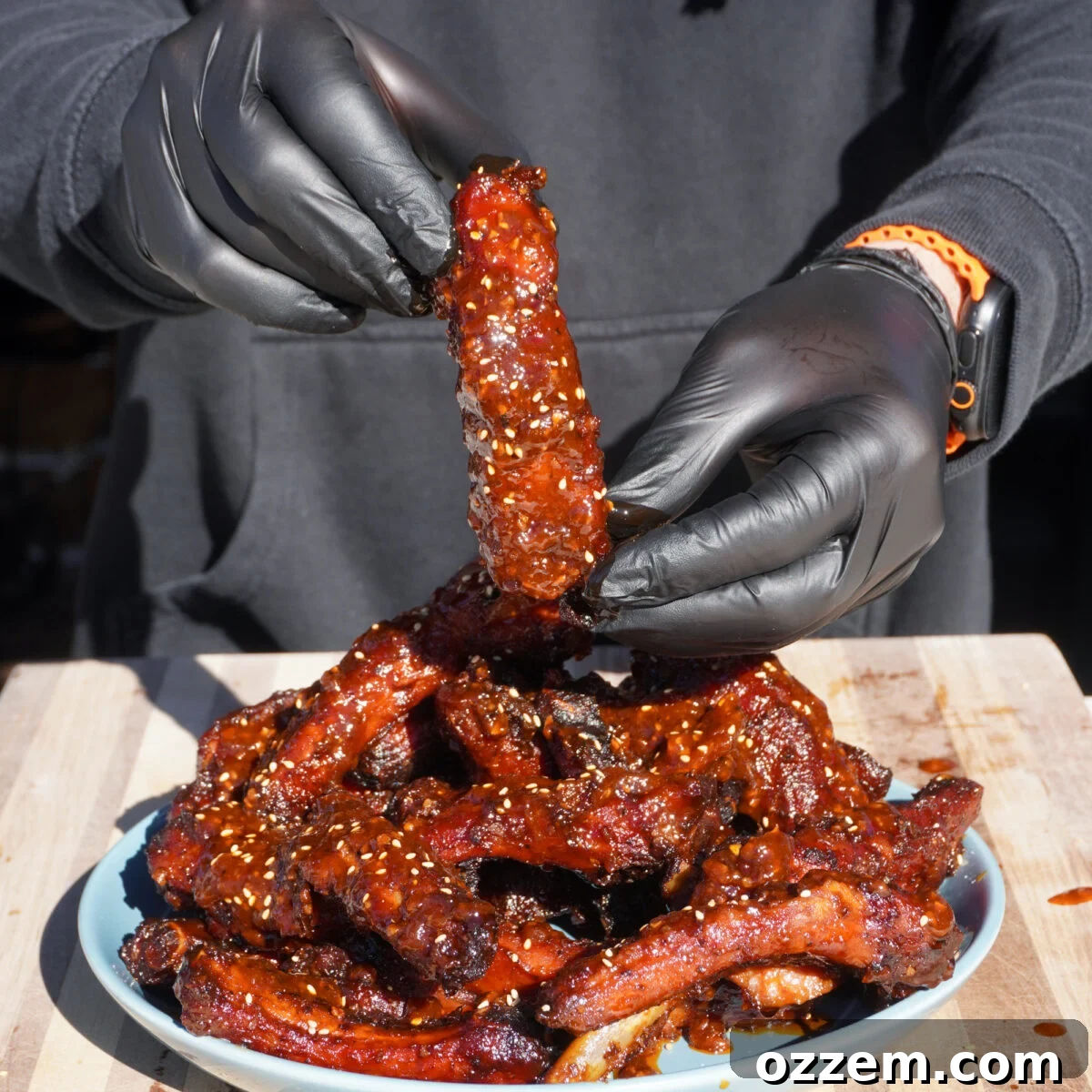 Ultimate Chili Crunch Ribs 2 Chili Crunch Party Ribs presented by hand, showcasing their sticky, caramelized glaze and vibrant color.