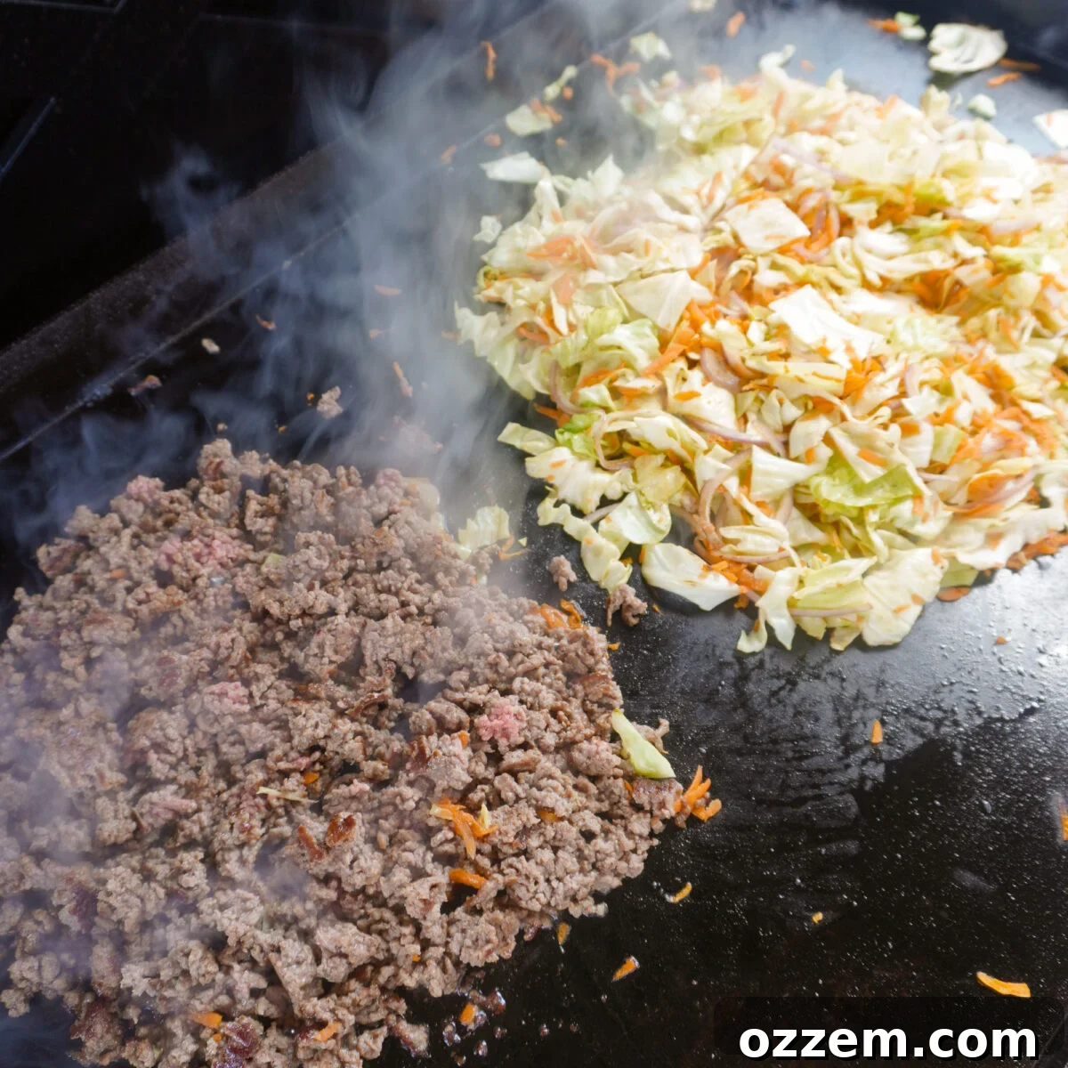 Cooked ground beef and various vegetables sautéing on a griddle.