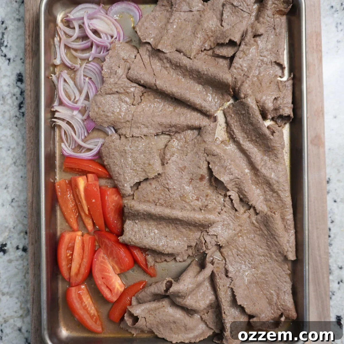 A sheet pan fresh from the oven, showcasing beautifully baked beef kebabs and roasted vegetables, still on the parchment paper.