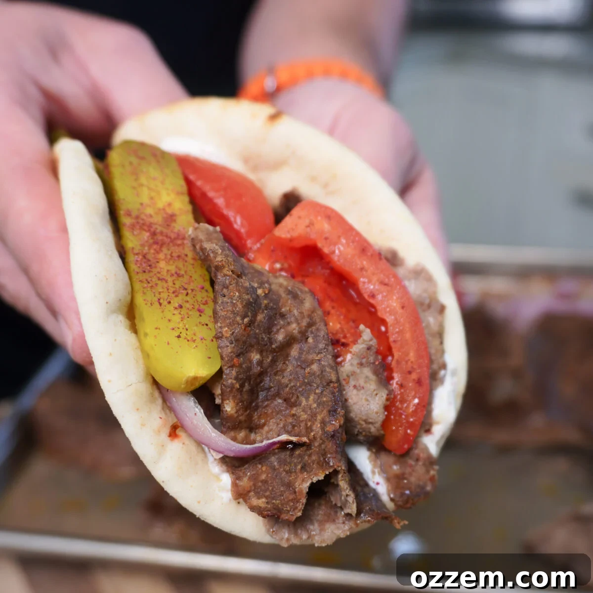 A perfectly assembled Sheet Pan Beef Kebab pita sandwich, brimming with juicy meat, roasted vegetables, and a creamy sauce.