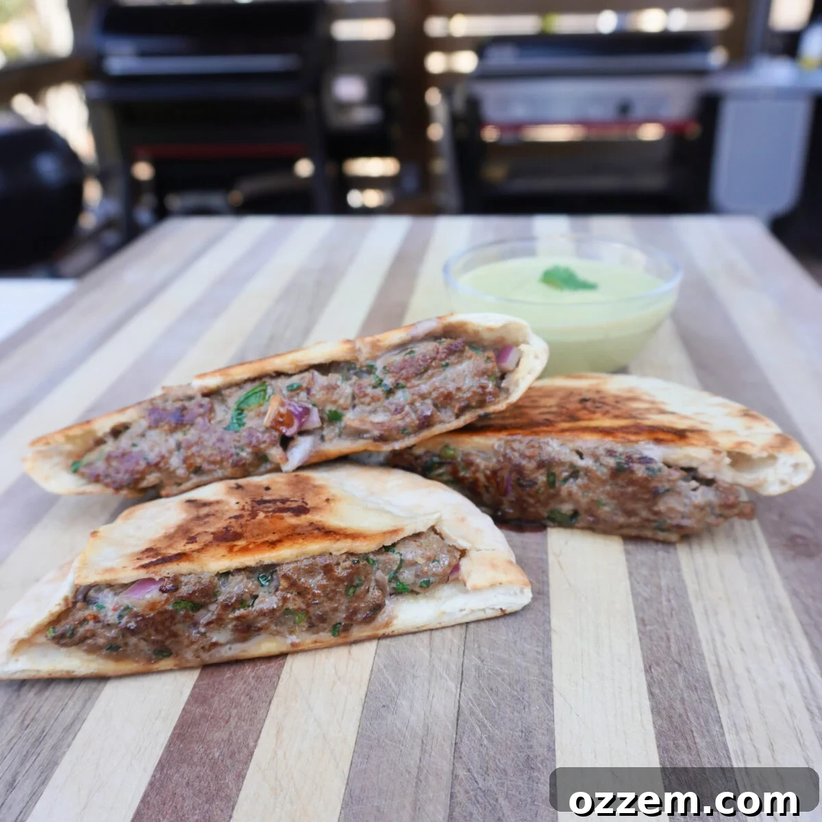 Grilled beef arayes on a cutting board, ready to be served with a vibrant green dipping sauce.