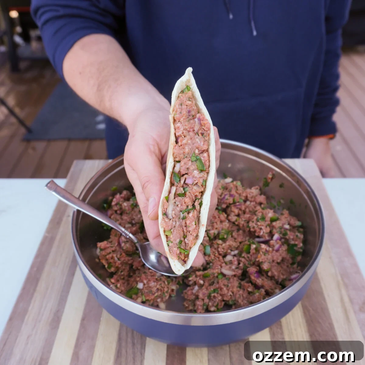 Pita bread halves generously stuffed with beef mixture, ready for grilling.