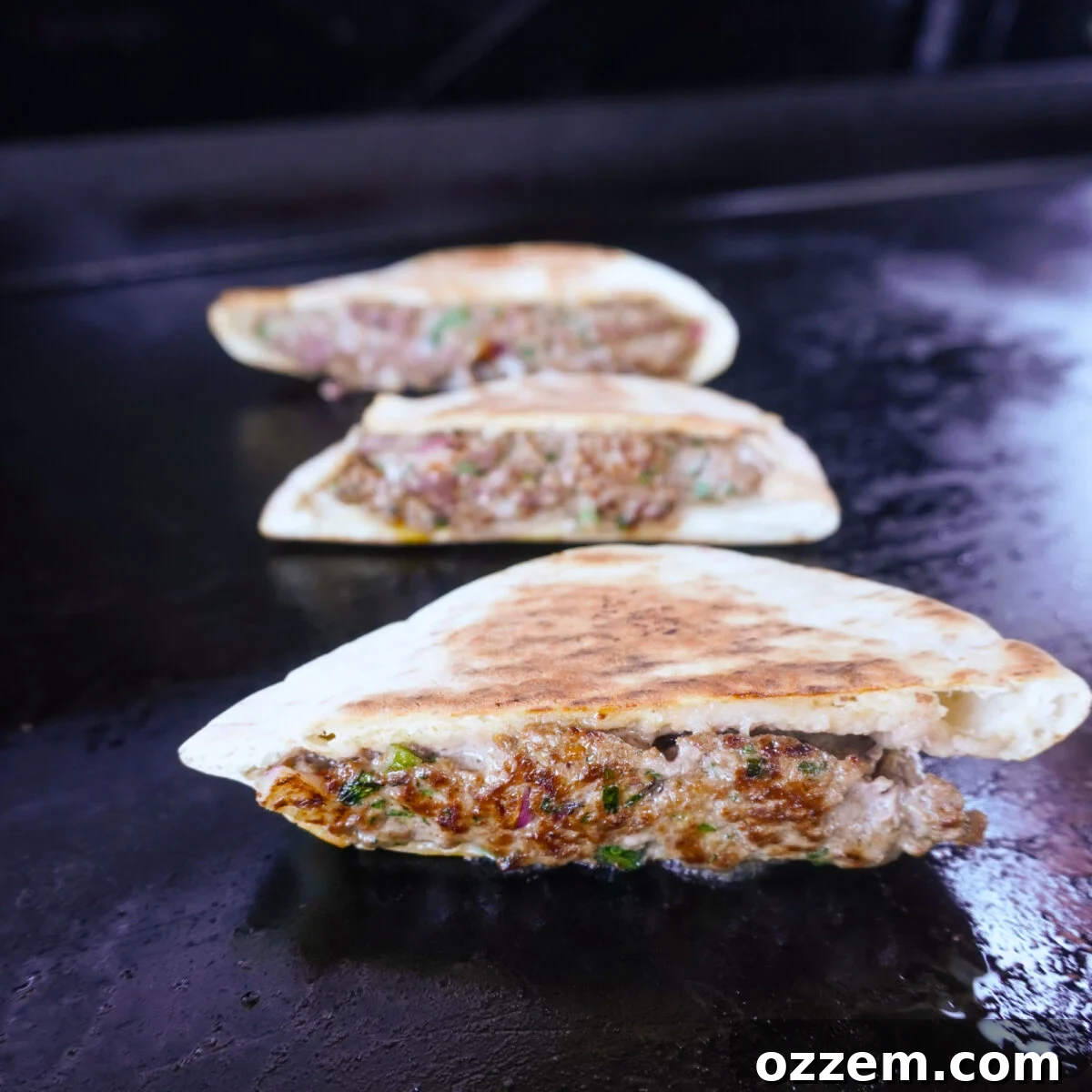 Grilled Beef Arayes sizzling on a hot griddle, achieving a perfect golden-brown crust.