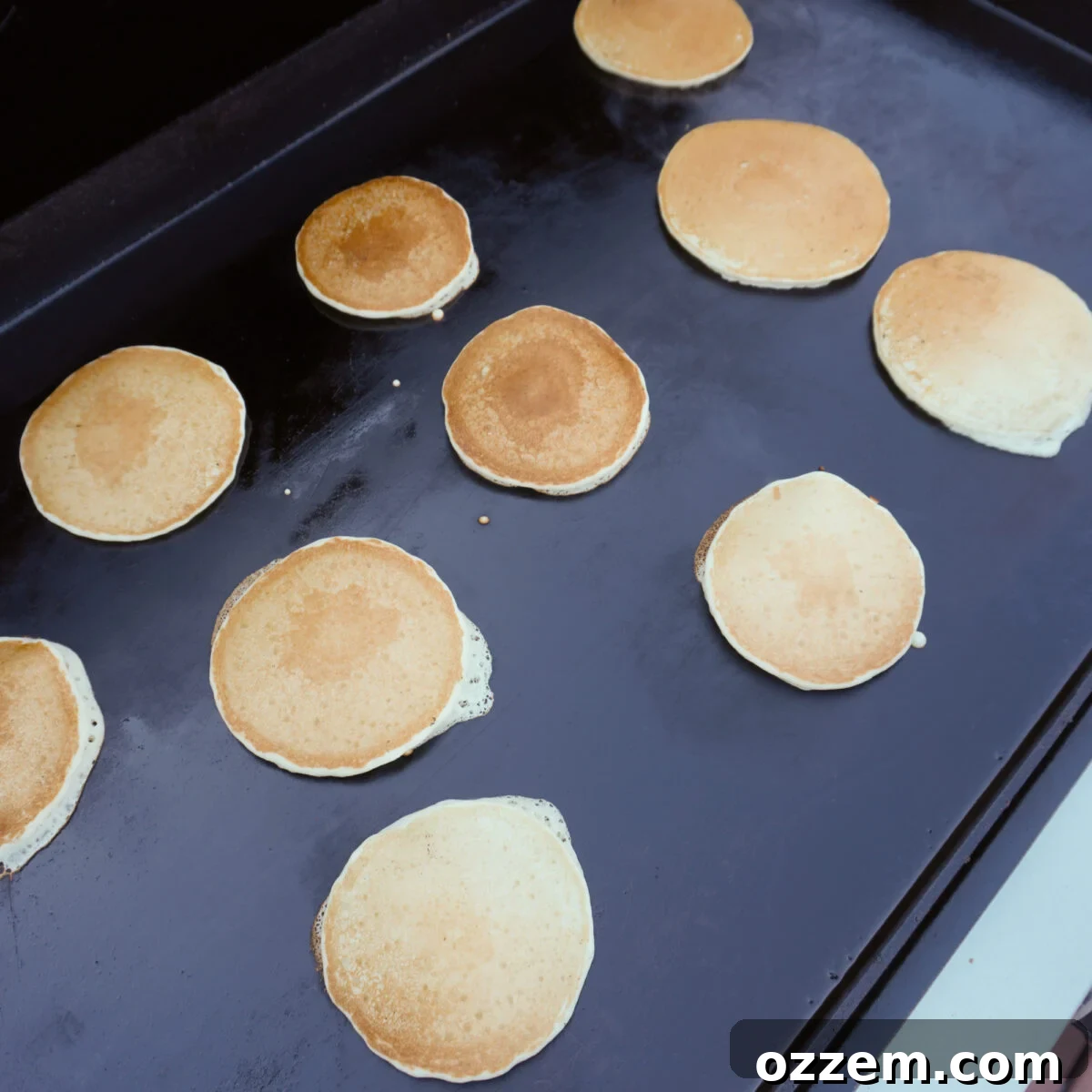 Golden-brown maple pancakes cooking on the griddle.