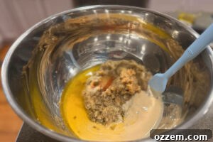 Large metal mixing bowl filled with chopped eggplant, tahini, and olive oil.