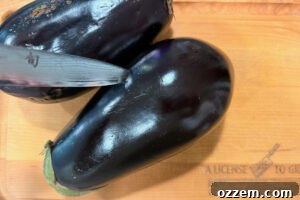 Piercing skin of eggplant with a knife.