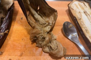 Scraping flesh from roasted eggplant.