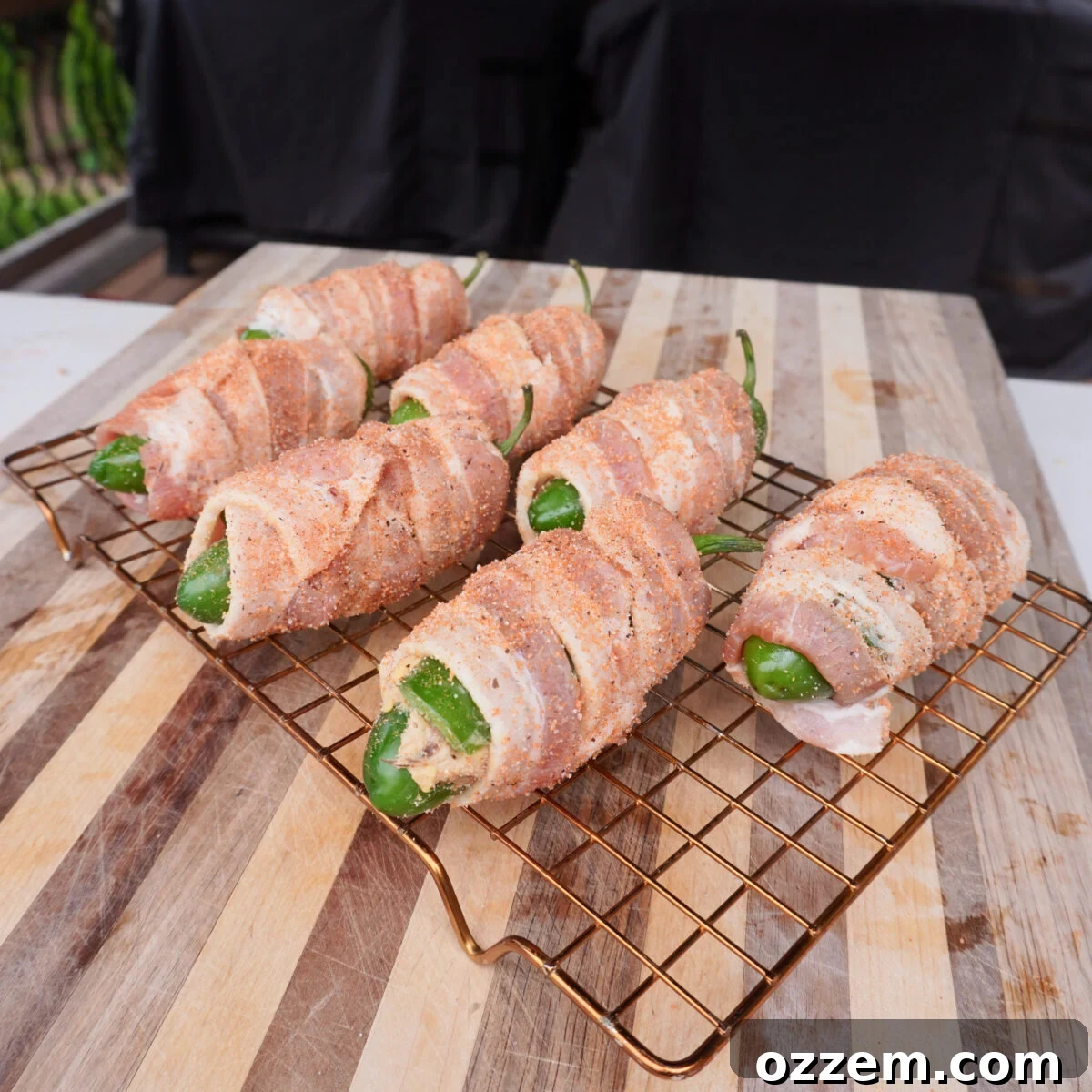 Pulled Pork-Stuffed Jalapeño Poppers: Smoky, Cheesy Bites 7 seasoned and bacon wrapped jalapeno poppers on a wire rack.