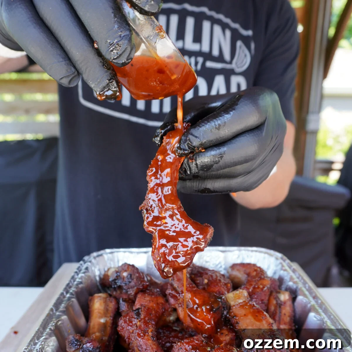 Smoked Sweet and Spicy Party Ribs with extra sauce being poured over.