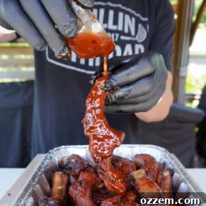 Smoked Sweet and Spicy Party Ribs with extra sauce being poured over.