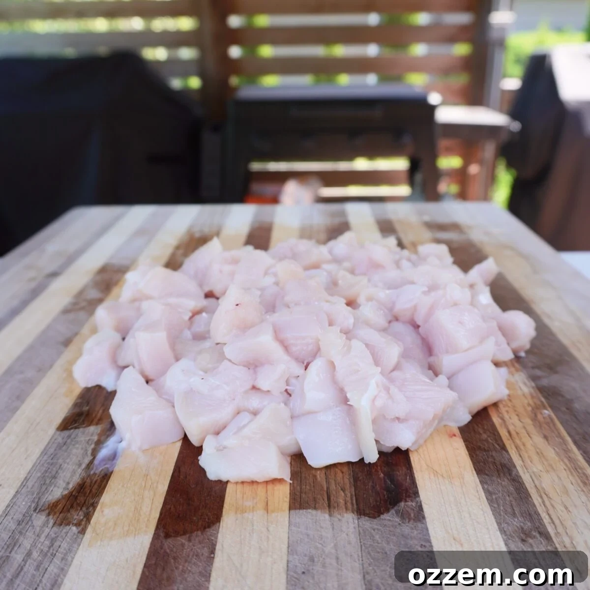 raw cubed chicken breast on wooden cutting board.