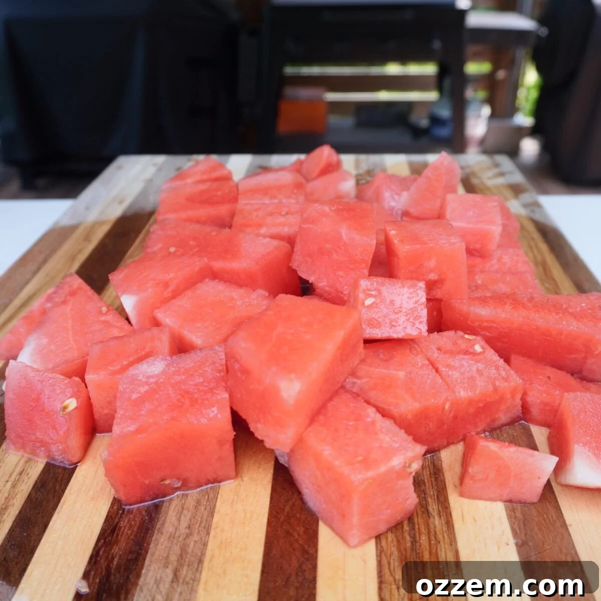 How to Make Refreshing Watermelon Juice at Home 4 cubed up watermelon on wooden cutting board.