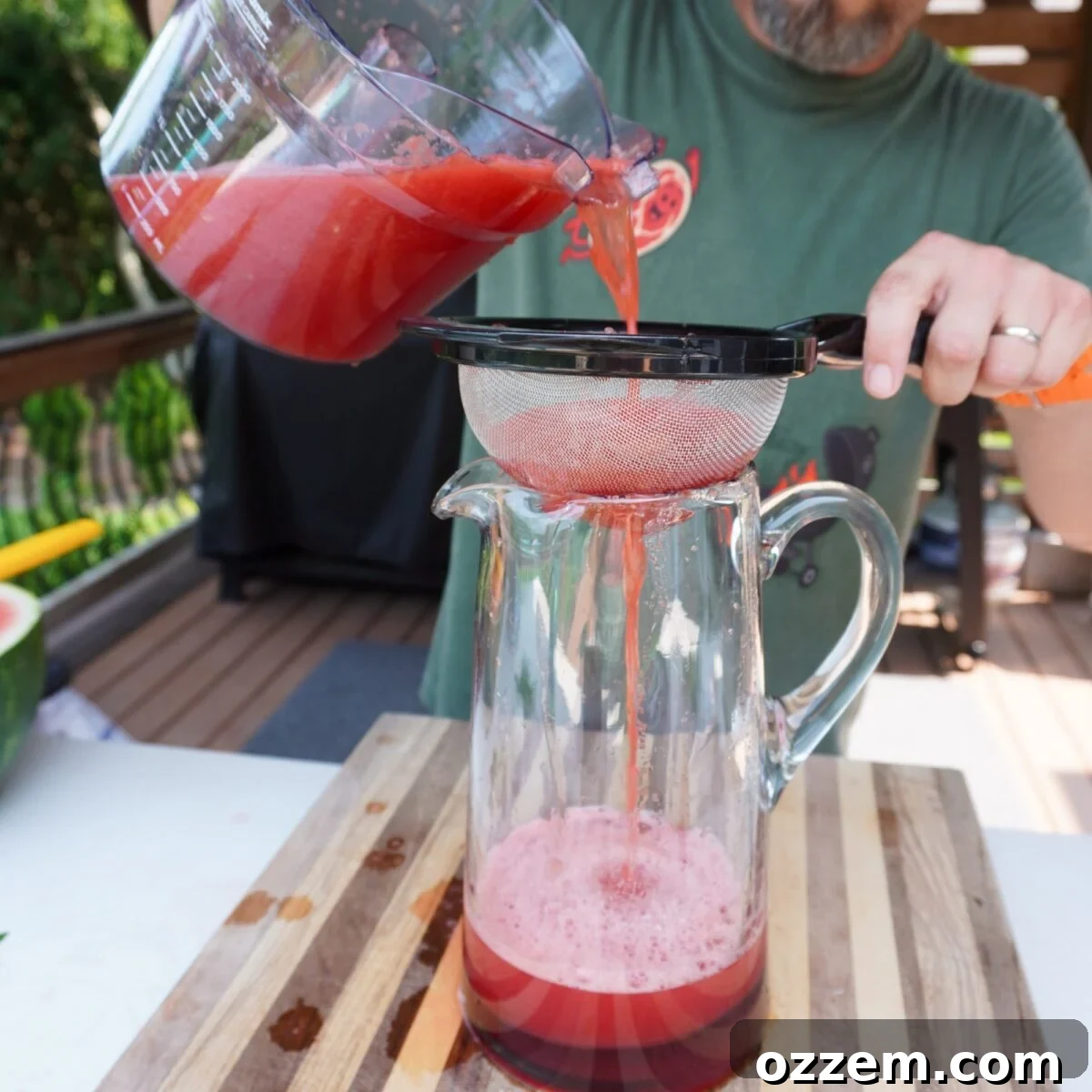 How to Make Refreshing Watermelon Juice at Home 5 draining watermelon juice through drainer into a pitcher.