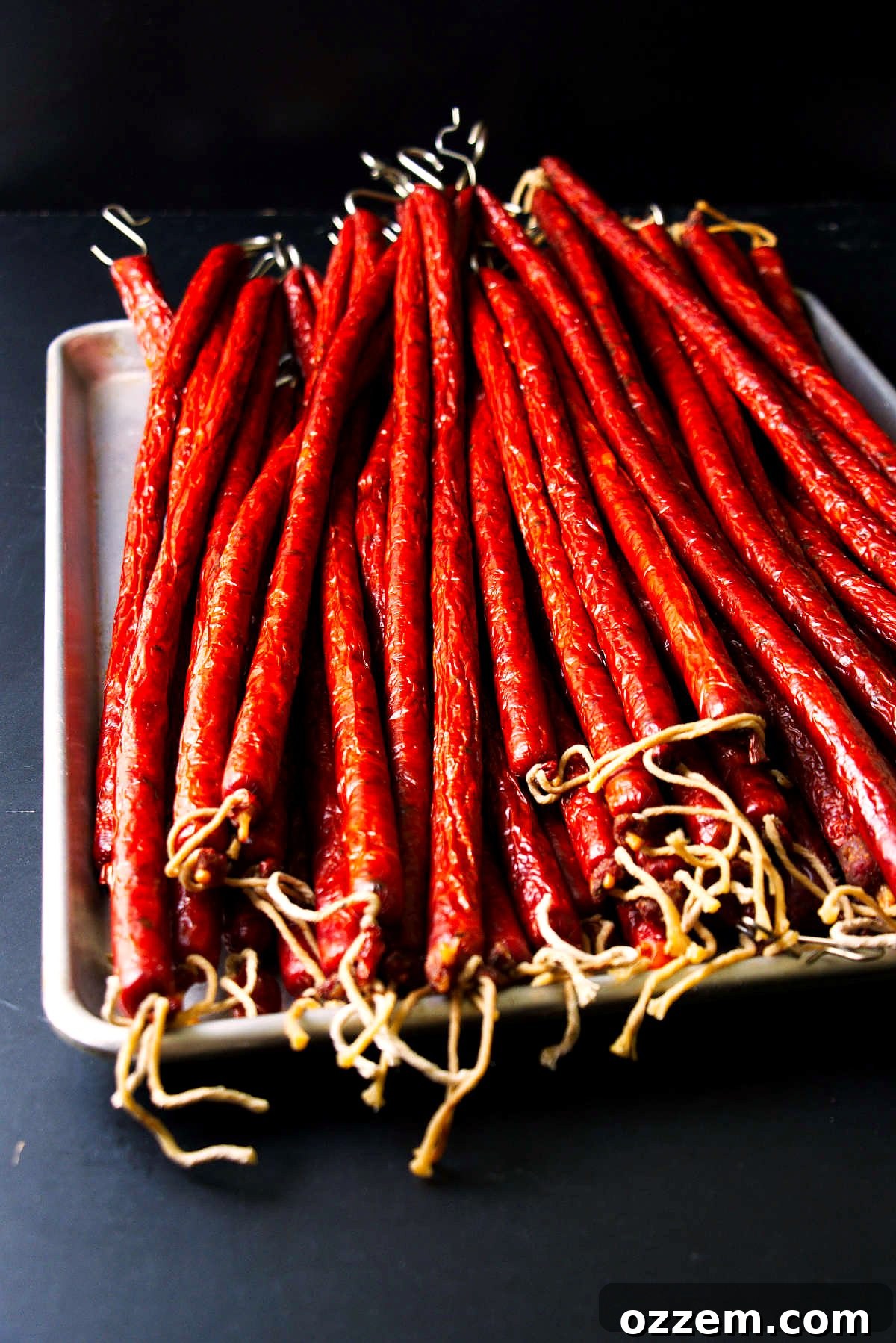 Spicy Jalapeño Cheddar Venison Snack Sticks Recipe 4 Venison snack sticks smoked and stacked on a stainless sheet pan.